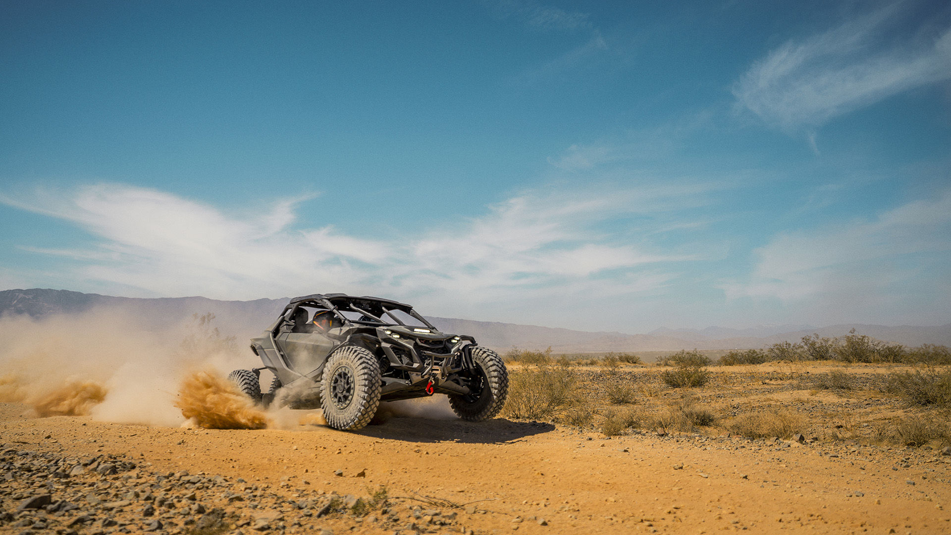 A 2026 Can-Am Maverick R X rc side by side riding on a desert trail under a blue sky