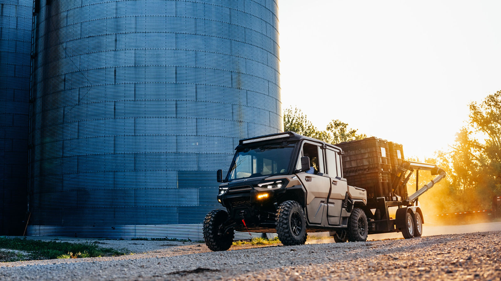 A 2027 Can-Am Defender HD7/HD9/HD10 pushing a load on a farm near a silo