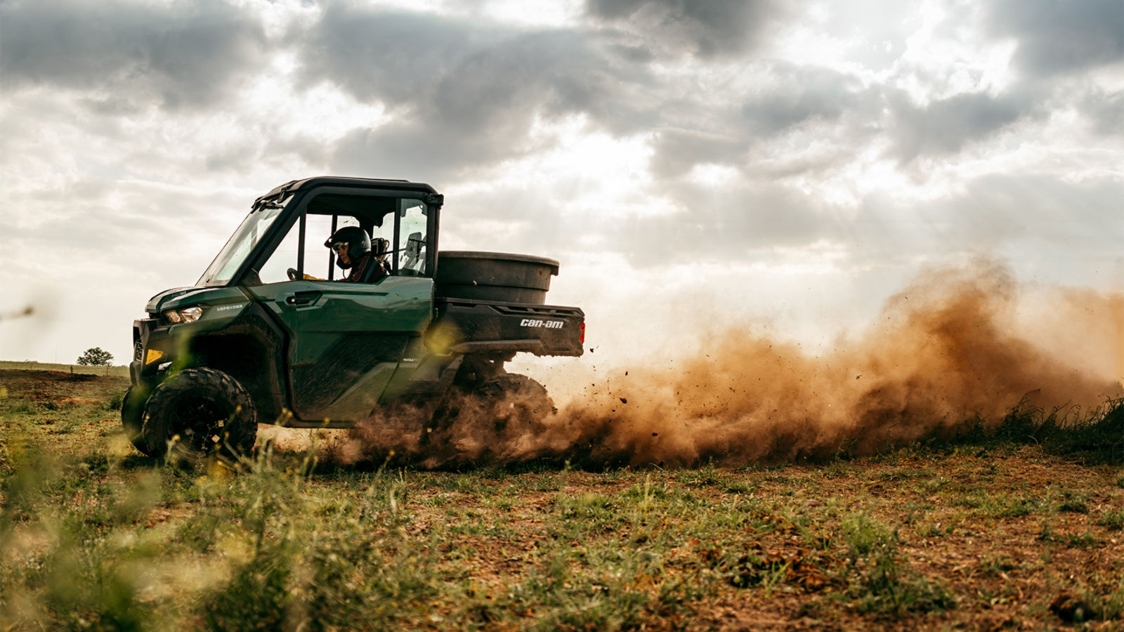 Un Can-Am Defender 2027 que recorre una finca, levantando una nube de polvo a su paso