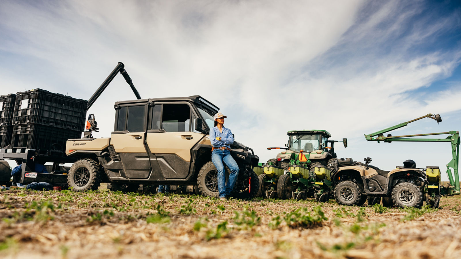 Una mujer sentada junto a su Can-Am Defender XU HD10/HD11, cerca de otros vehículos utilitarios