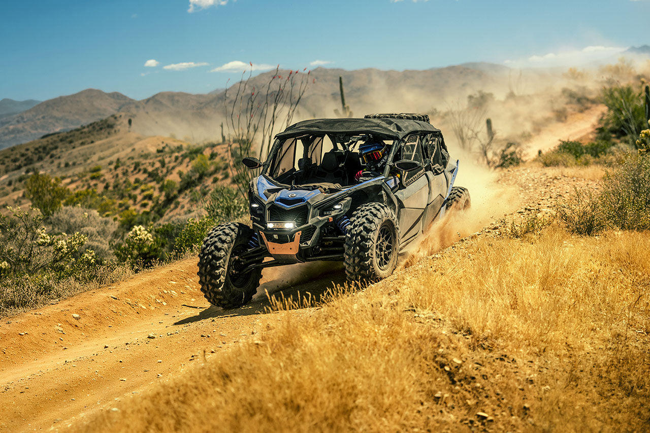 A rider in a 2027 Can-Am Maverick X3 side-by-side vehicle on a desert trail