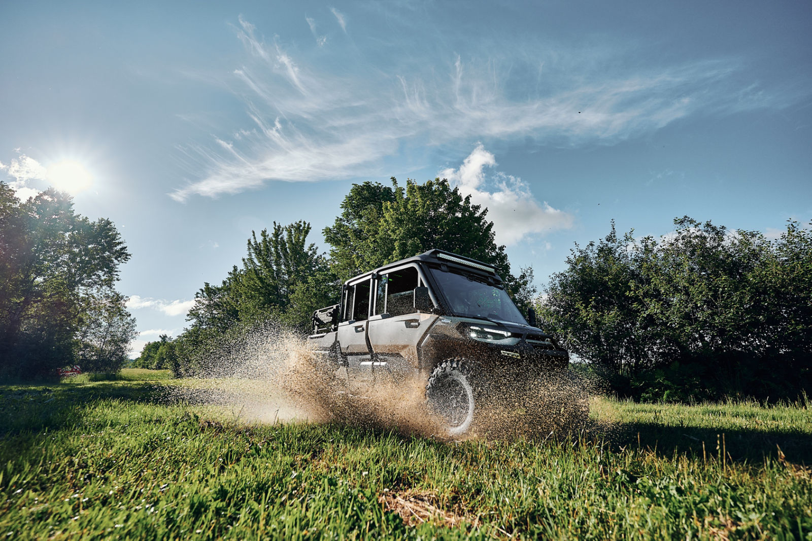 The new 2027 Can-Am Defender XU Limited SxS model driving through a mud puddle on a farm
