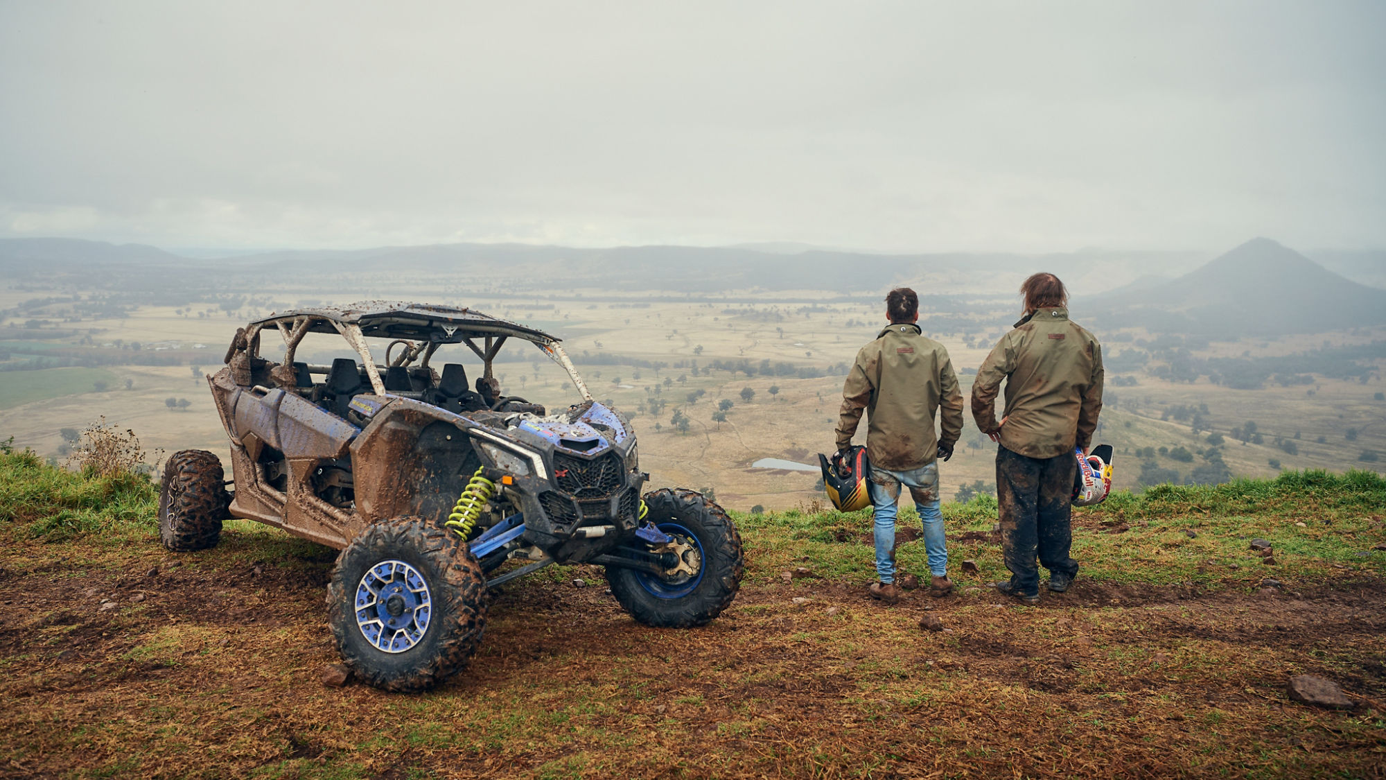 Toby Price and Shaun Whale standing next to a Can-Am Maverick X3 overlooking rolling hills.