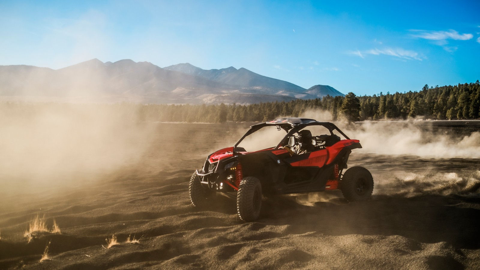 Two people in a Can-Am side-by-side on rocks in the desert