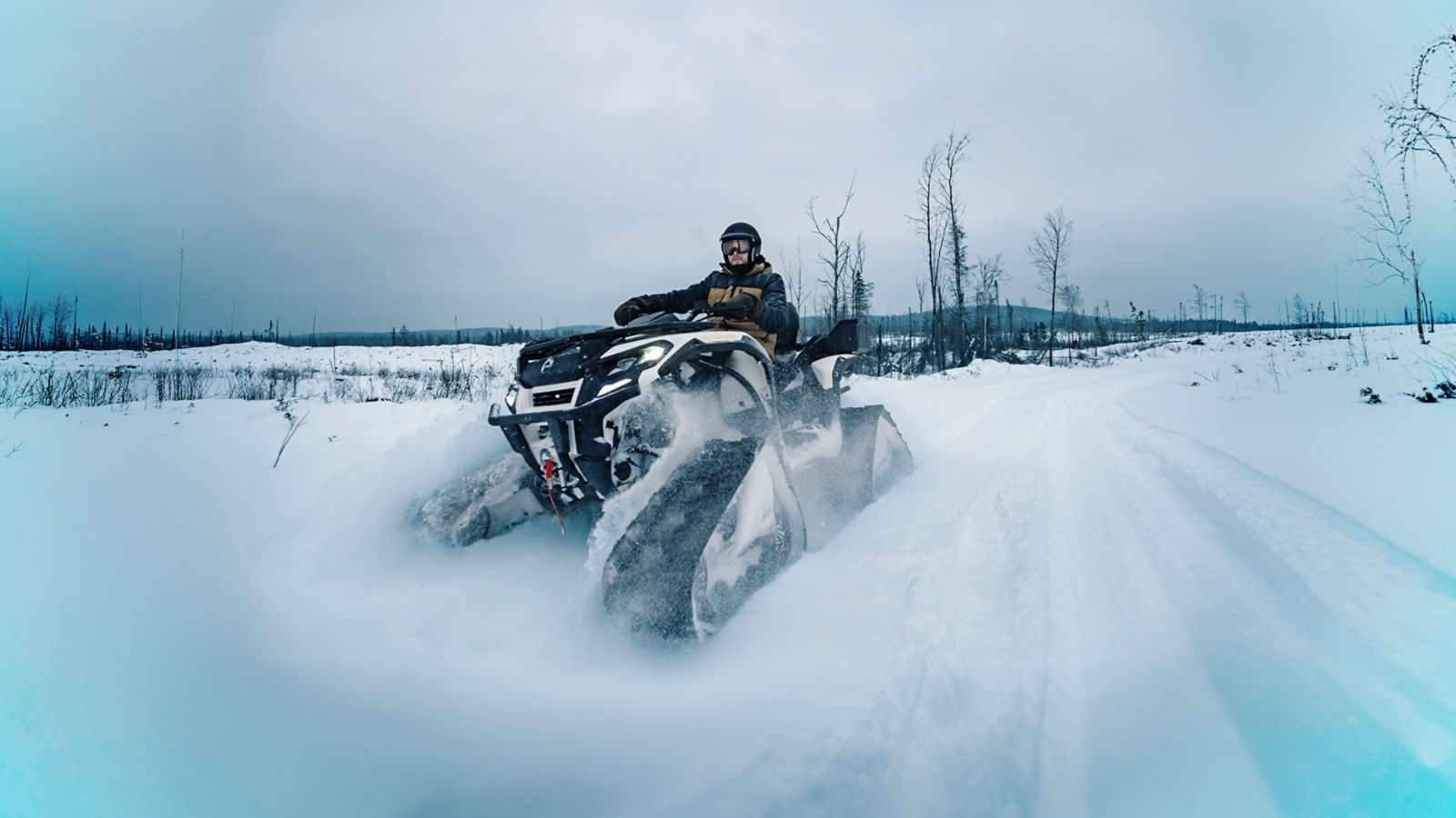 Rider on a white Can-Am ATV with apache tracks in deep-snow trail