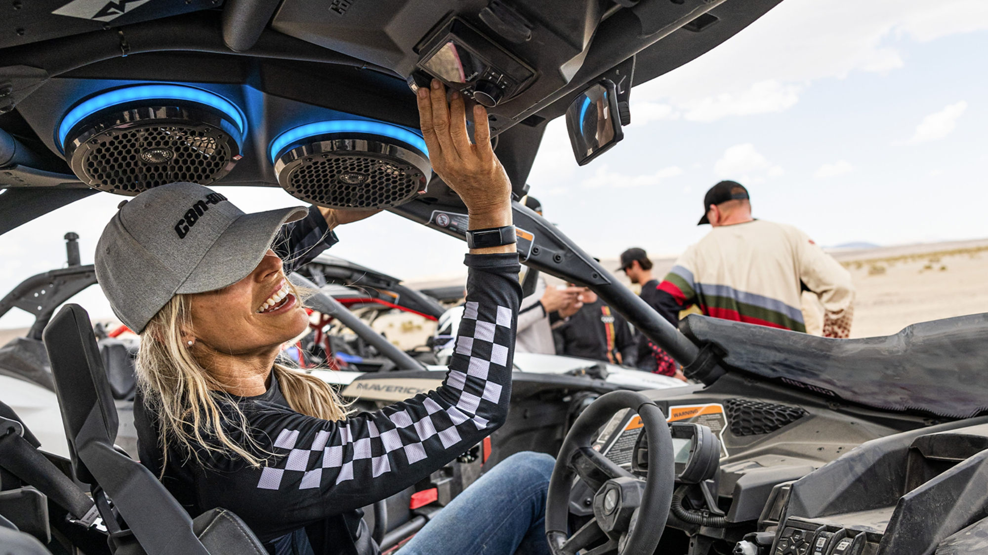 A driver making adjustments on her Can-Am Side-by-Side (SxS) audio roof.