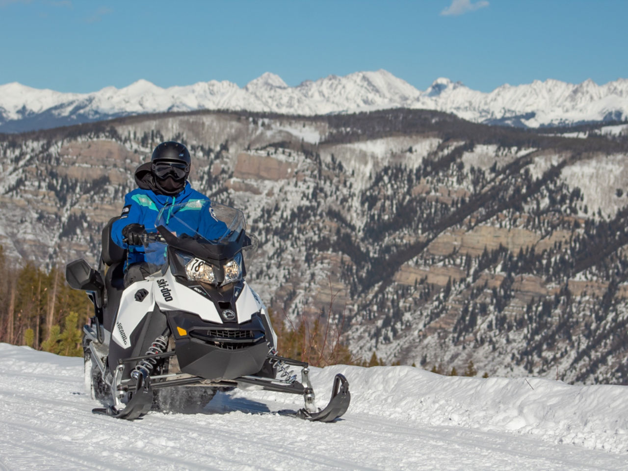 2 personnes sur un Ski-Doo dans les montagnes