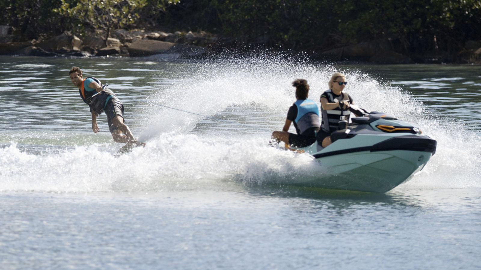 Woman riding a Sea-Doo Wake Pro with a passenger and pulling a wakeboarder