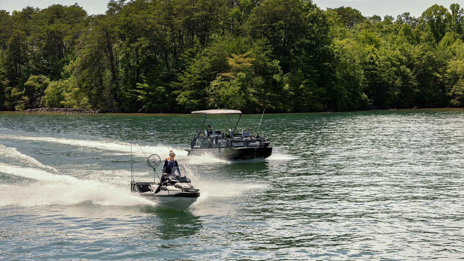 A woman riding a 2025 Sea-Doo personal watercraft and a man riding a 2025 Sea-Doo pontoon boat.