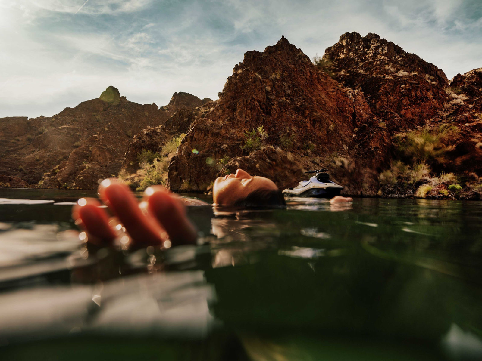 A woman swimming next to her 2025 Sea-Doo Spark Trixx personal watercraft