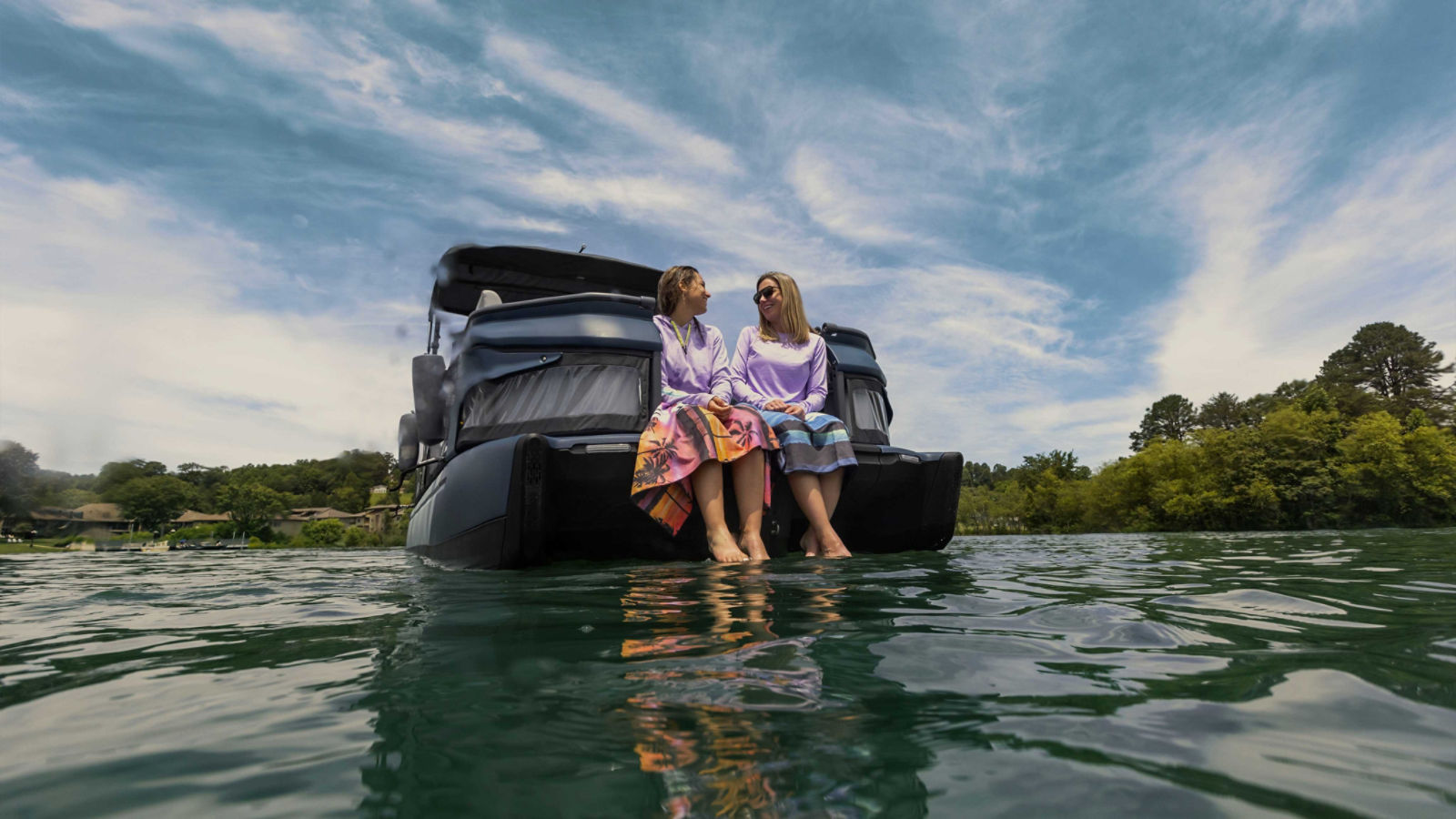 Two women sitting on the platform of a 2025 Sea-Doo Switch Limited pontoon