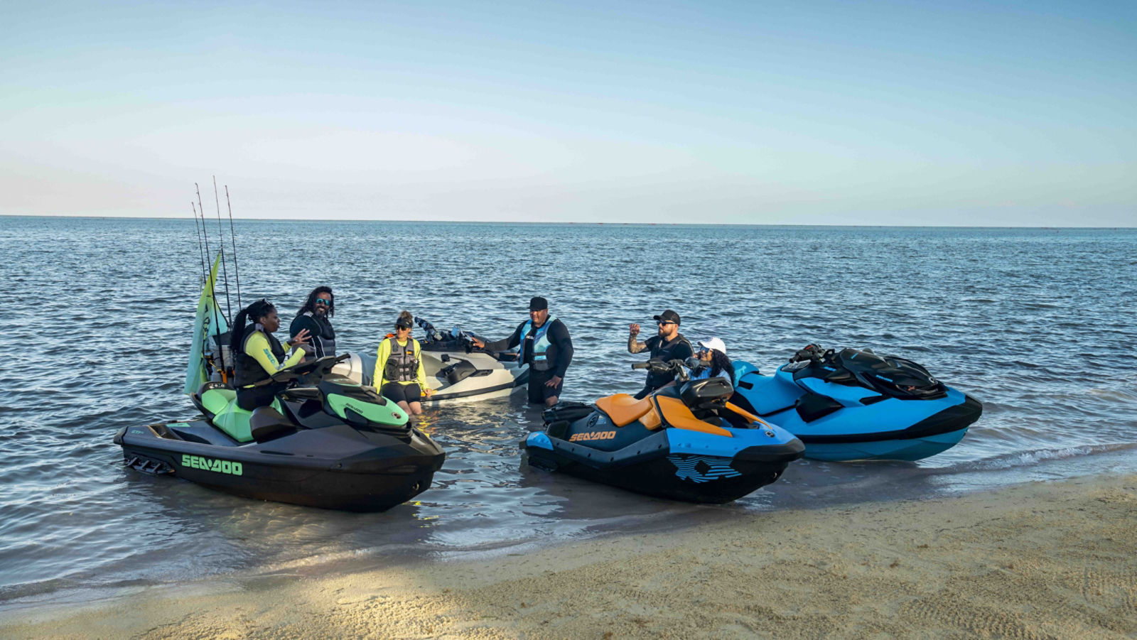 A group of friends on several Sea-Doo personal watercraft docked on the beach
