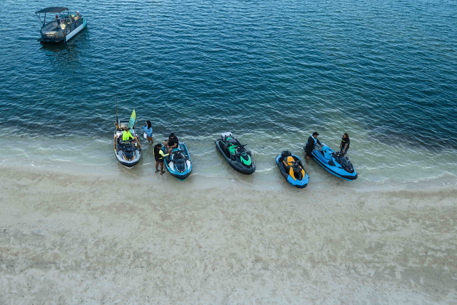 偏光レンズのサングラスをかけた男性が水中から顔をのぞかせ、その後ろには2台のSea-Dooが浮かび、そのうちの1台には女性が乗っている