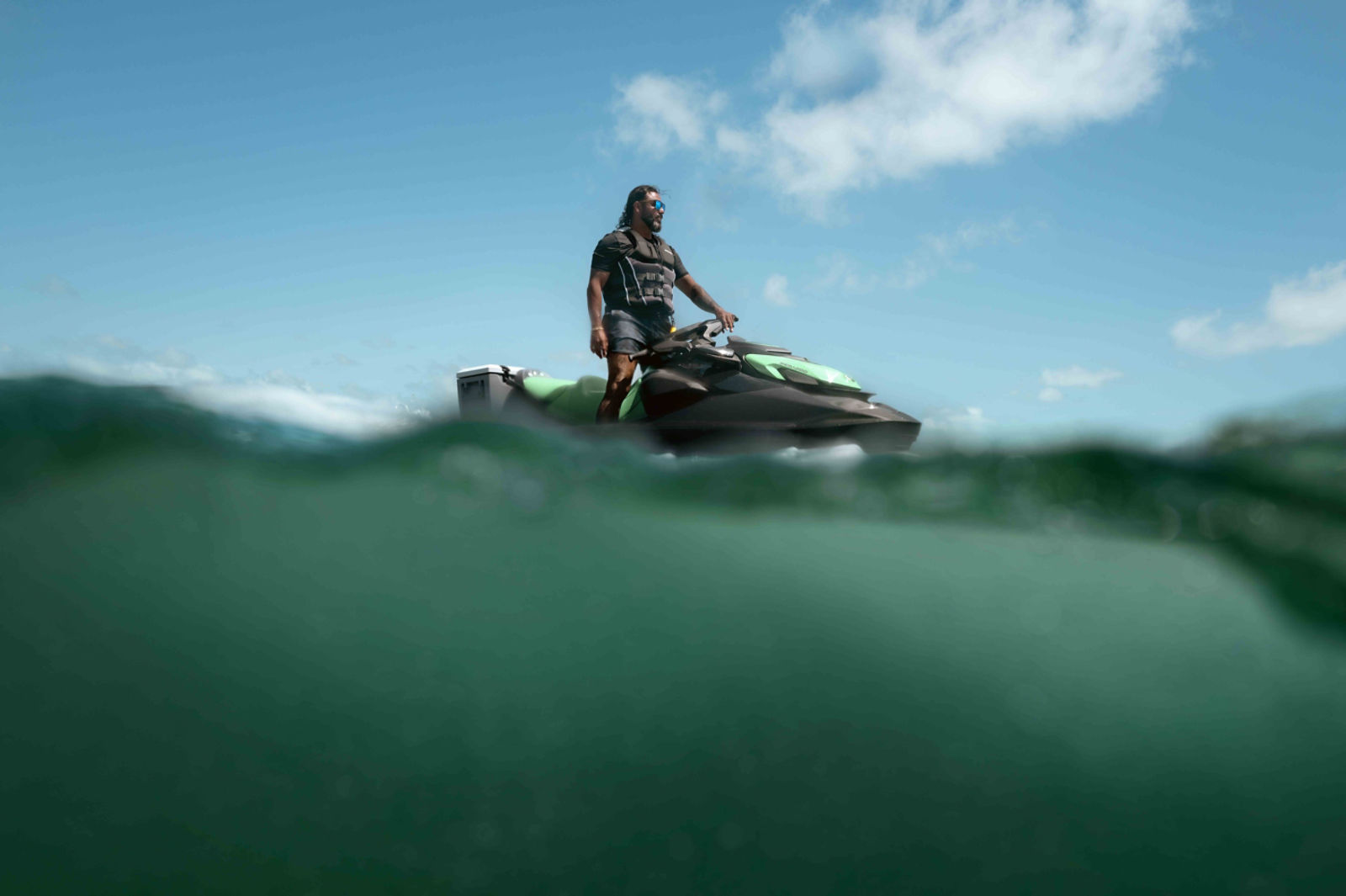 Un hombre de pie sobre su moto acuática Sea-Doo GTI SE 2026.