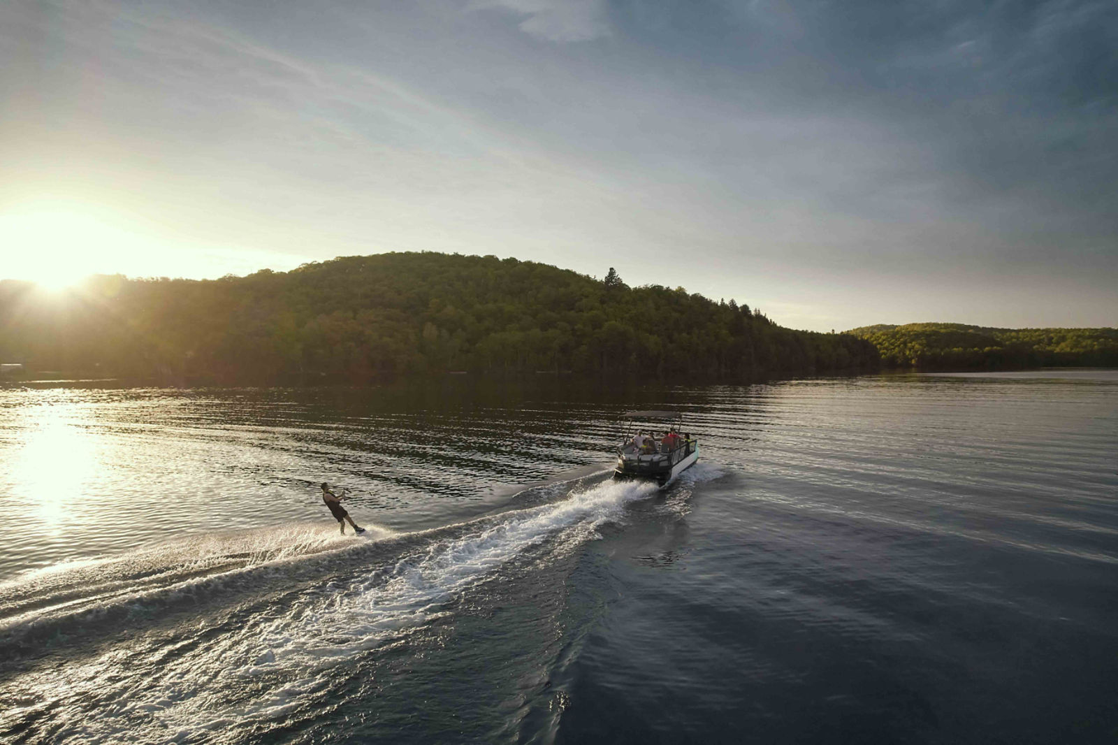 A young man being pulled by the 2026 Sea-Doo Switch Sport 21 pontoon on a calm lake