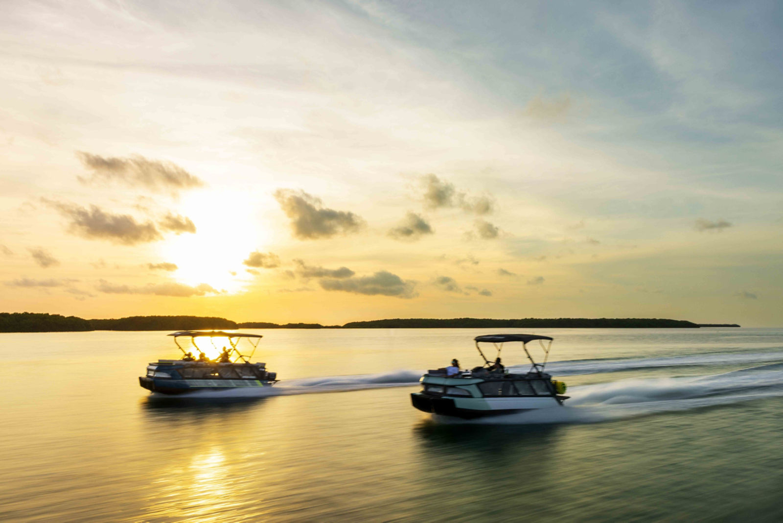 Two 2026 Sea-Doo Switch Cruise pontoon boat on the water with a sunset