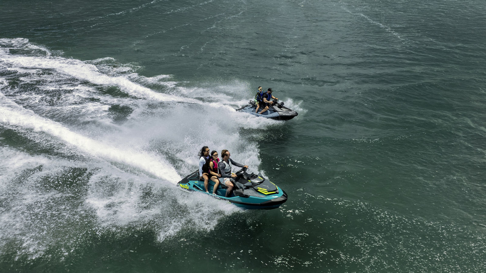 Two people riding a Sea-Doo Spark X 110 and a Sea-Doo Wake Pro 230