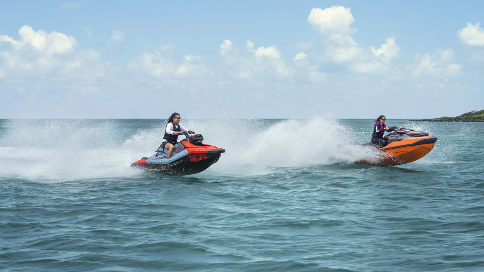 Zwei Frauen fahren mit hoher Geschwindigkeit auf Sea-Doo Jetskis