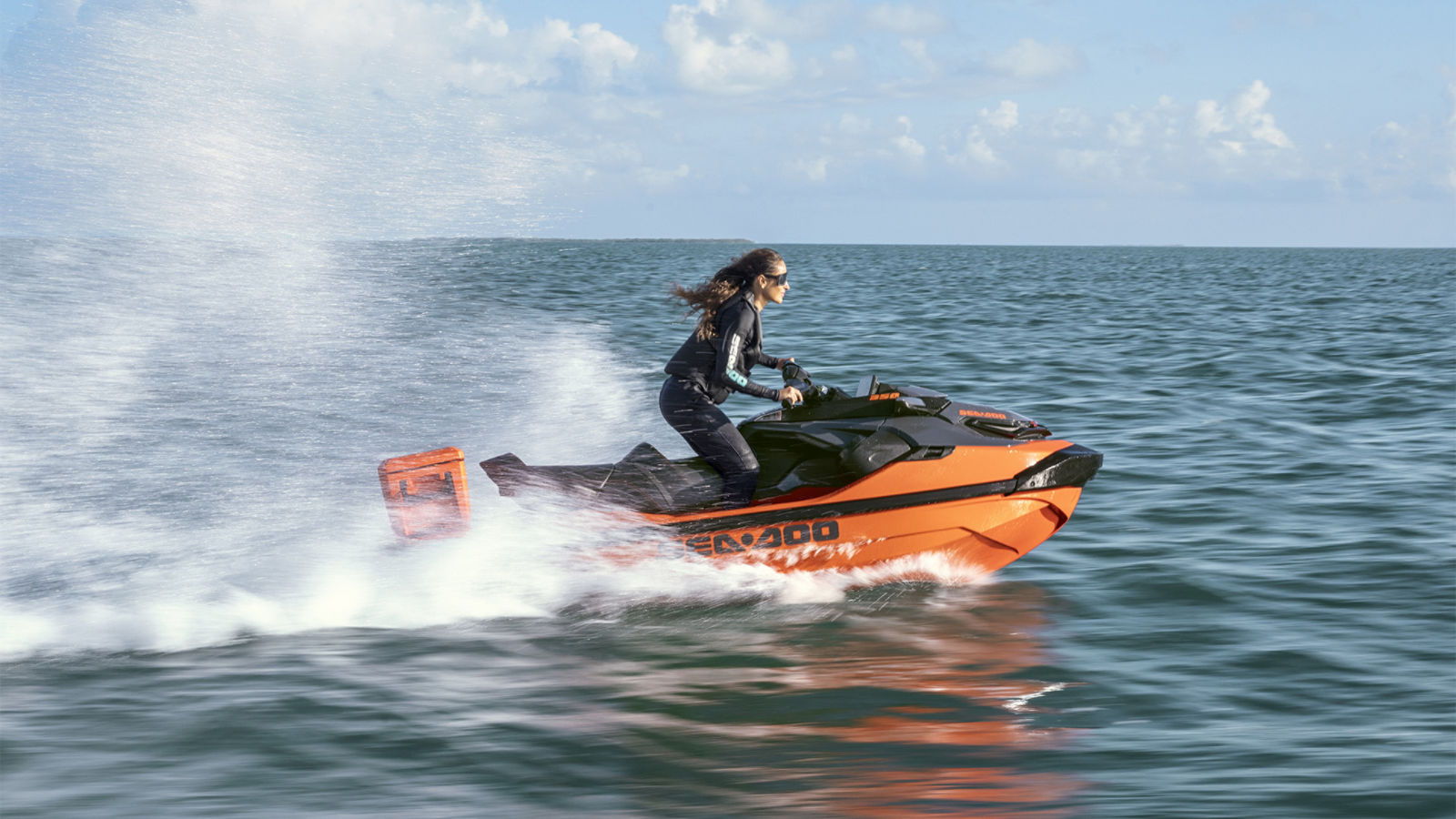 A woman riding a 2027 Sea-Doo RXT-X personal watercraft at full speed
