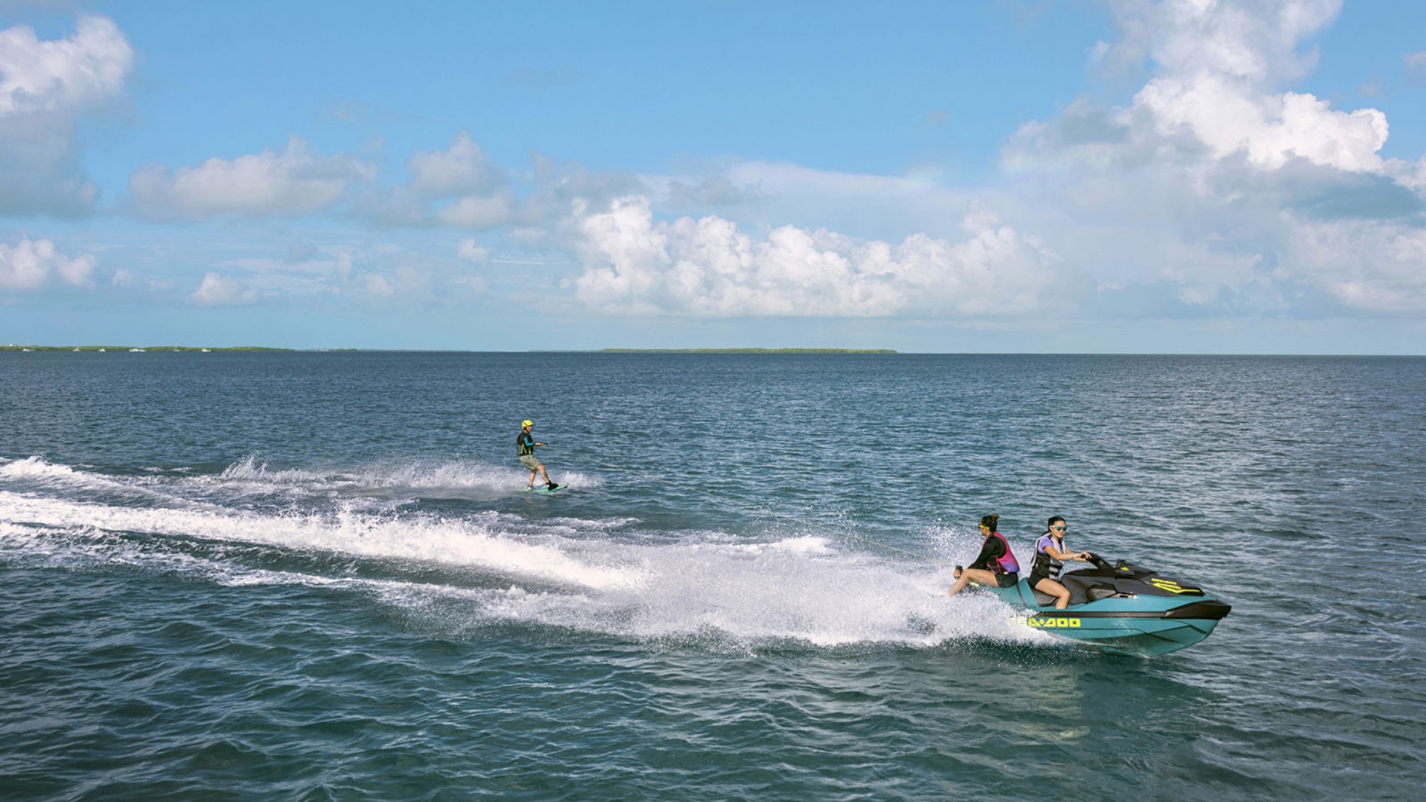 A person water-skiing behind a 2027 Sea-Doo Wake Pro personal watercraft on a lake