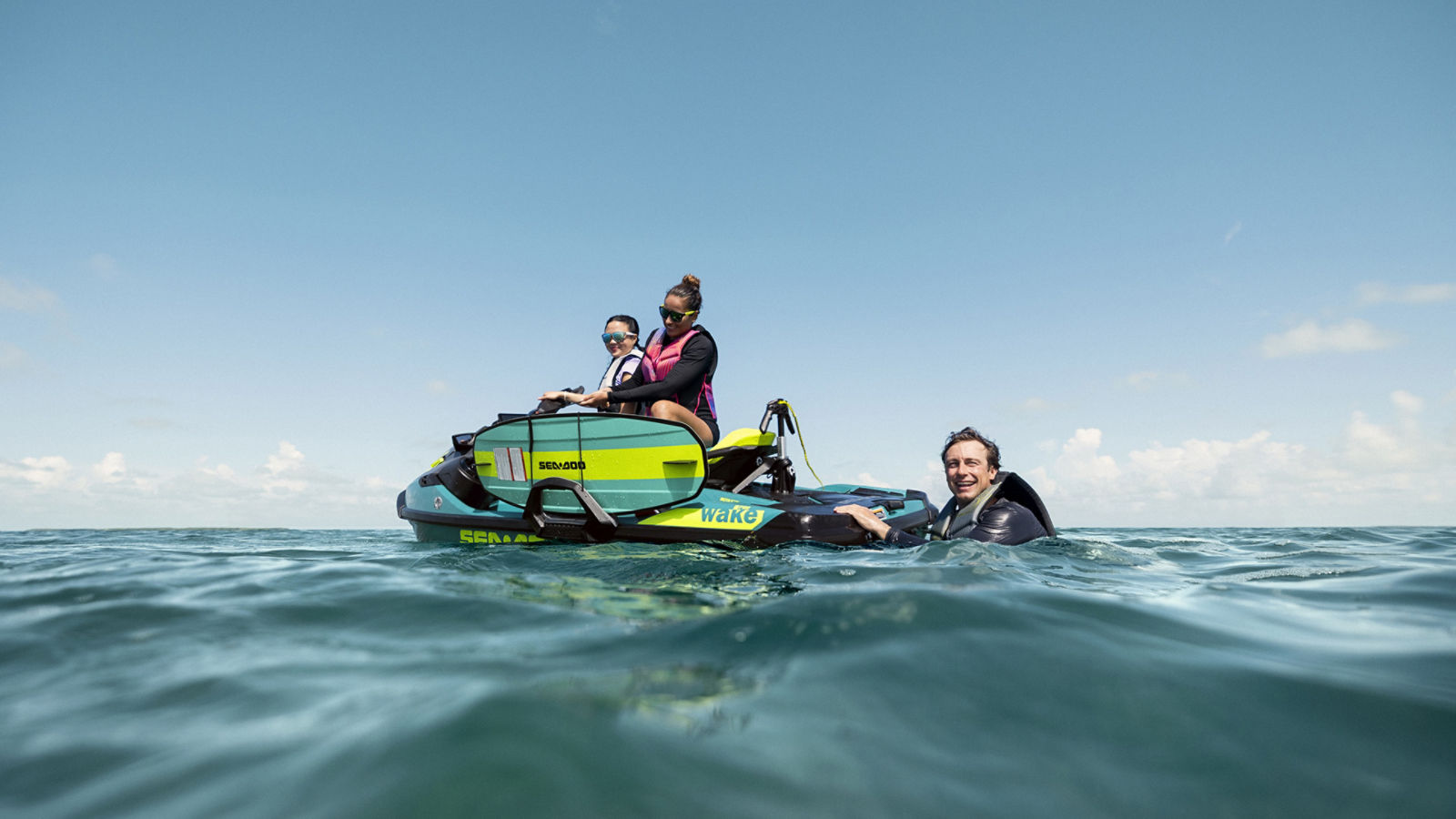 Two people on a 2027 Sea-Doo Wake Pro fully equipped for water sports and one person in the water