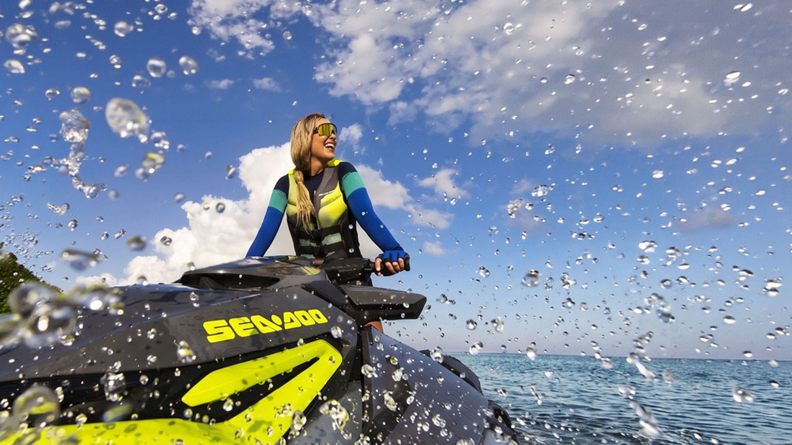 A woman wearing Sea-Doo gear on her personal watercraft on a sunny day