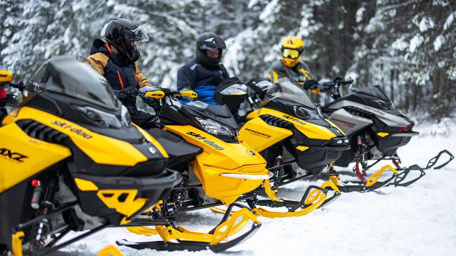 Four riders on their Ski-Doo snowmobiles about to head out on a trail