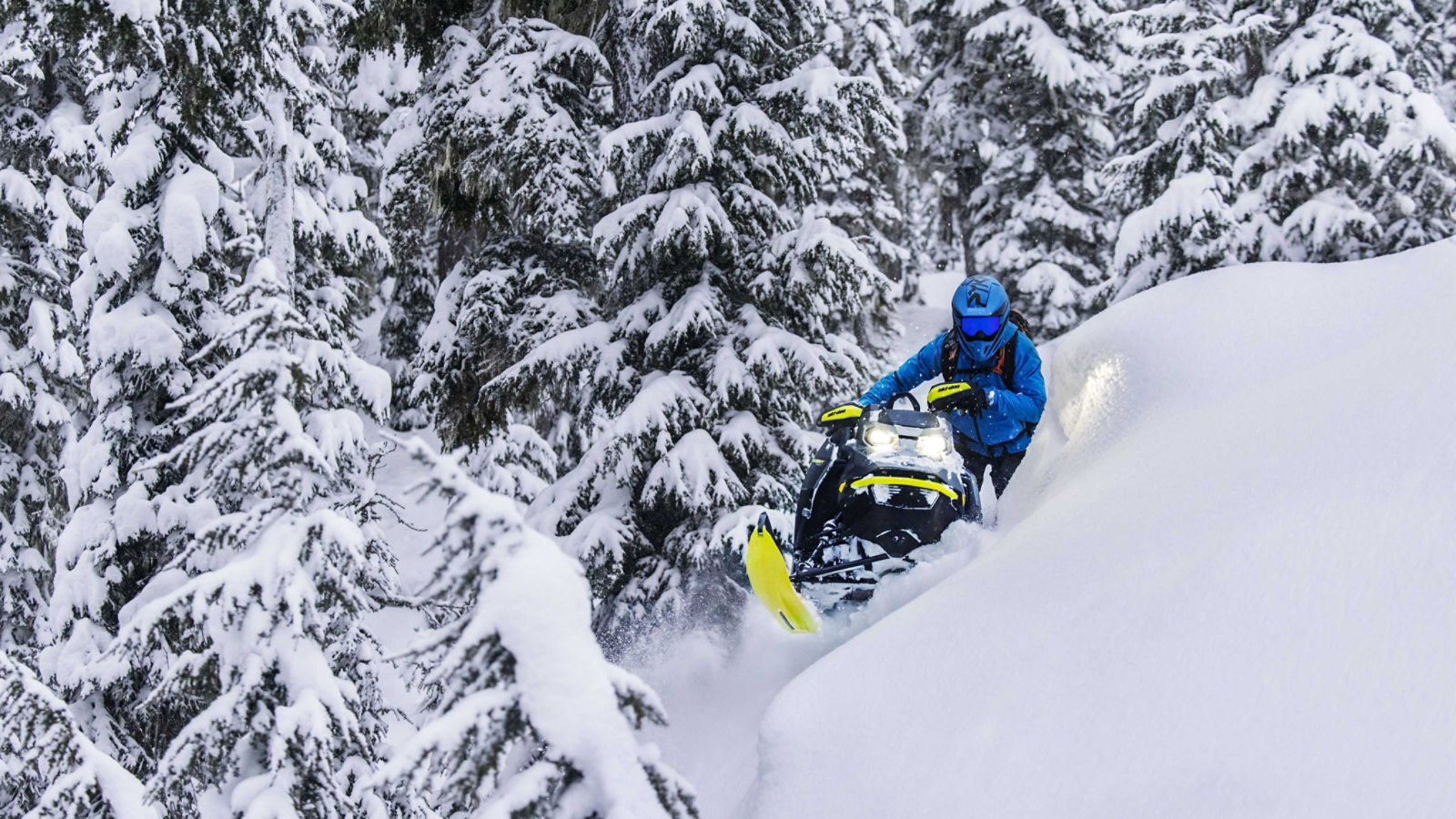 Mann kjører en Ski-Doo på en teknisk sidebakke