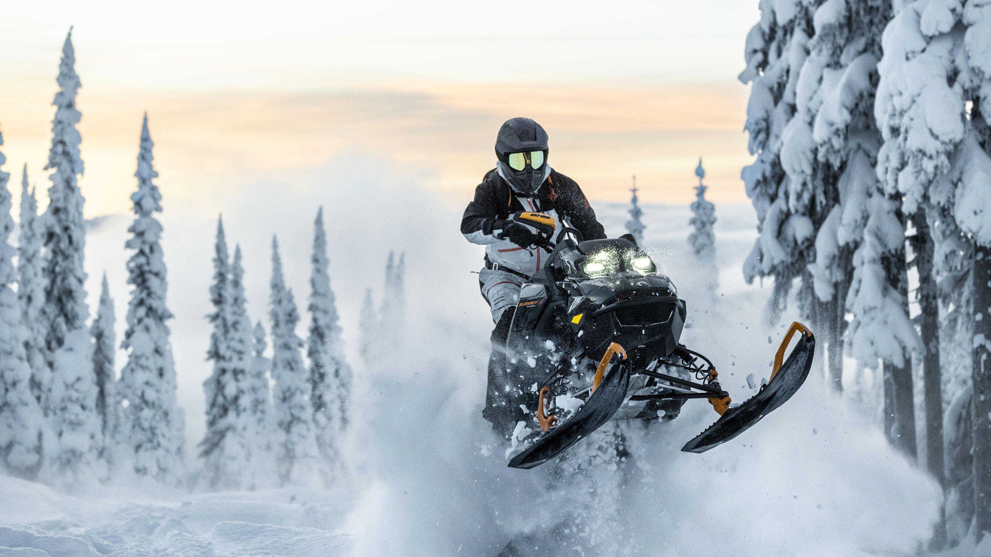 Group of snowmobilers looking at a cellphone next to their sleds