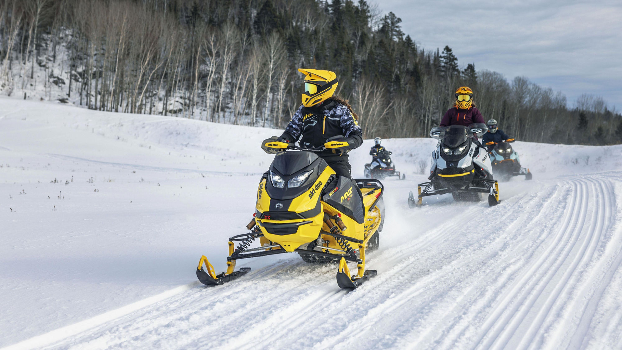Quatre motoneigistes sur des Ski-Doo en sentier