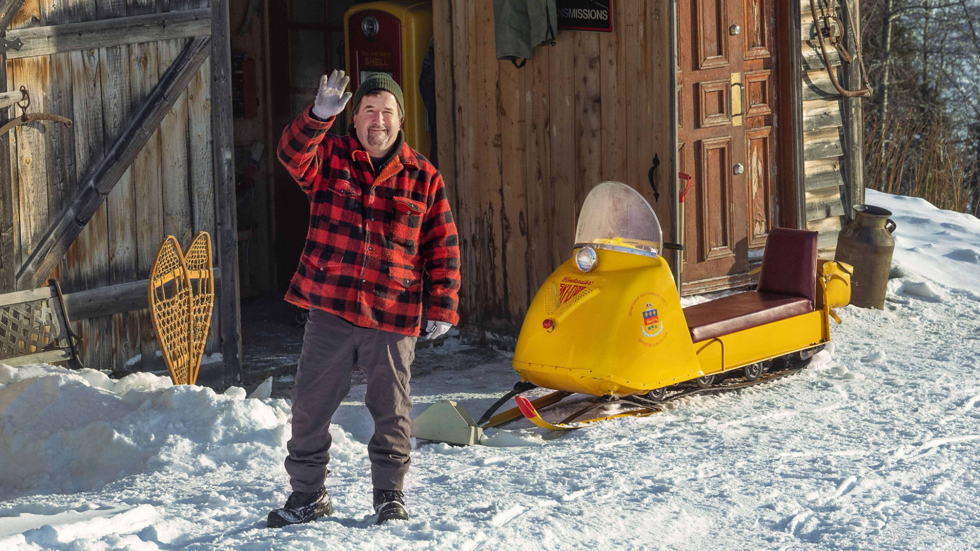 Homme saluant des motoneigistes à côté d'une motoneige Ski-Doo vintage