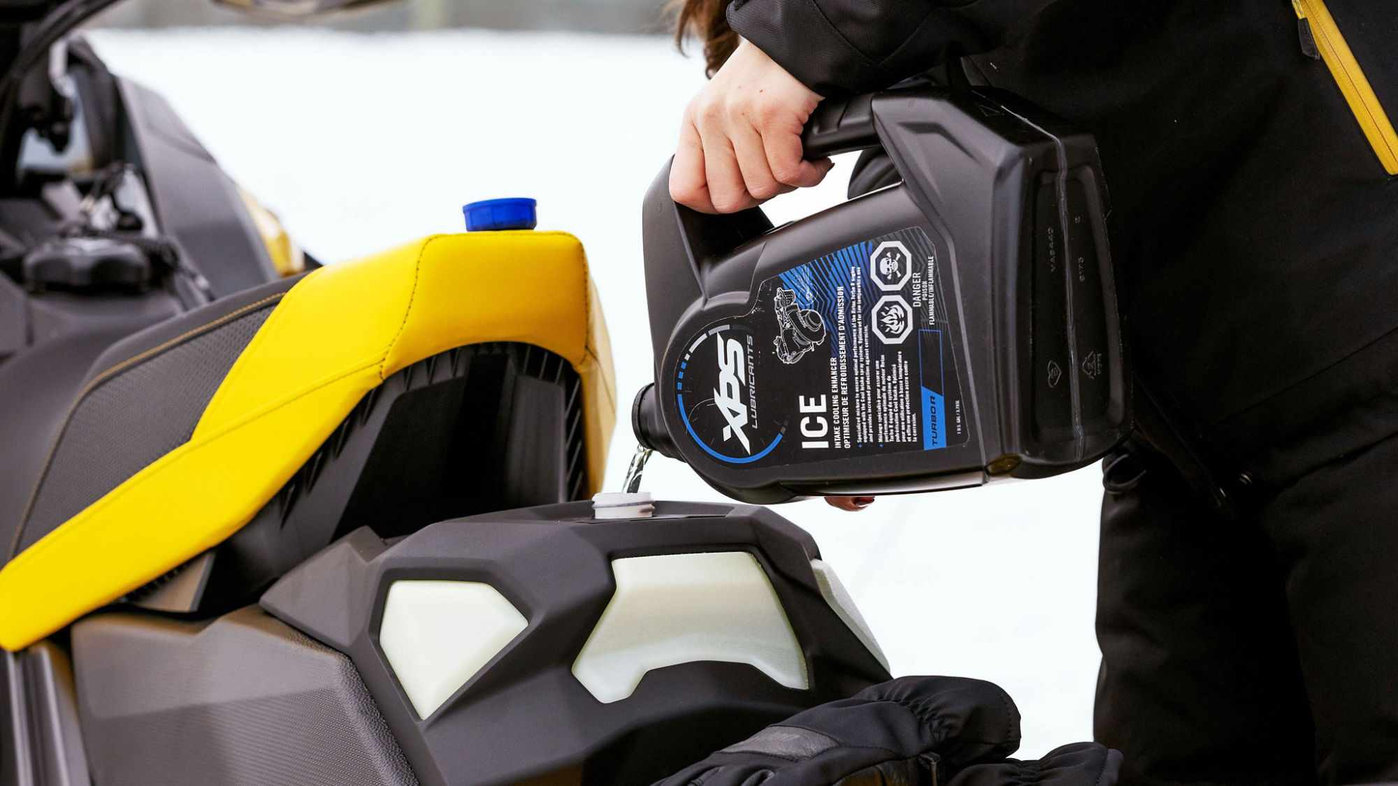 Personne ajoutant du liquide XPS ICE à un ensemble de compétition Ski-Doo MXZ X-RS