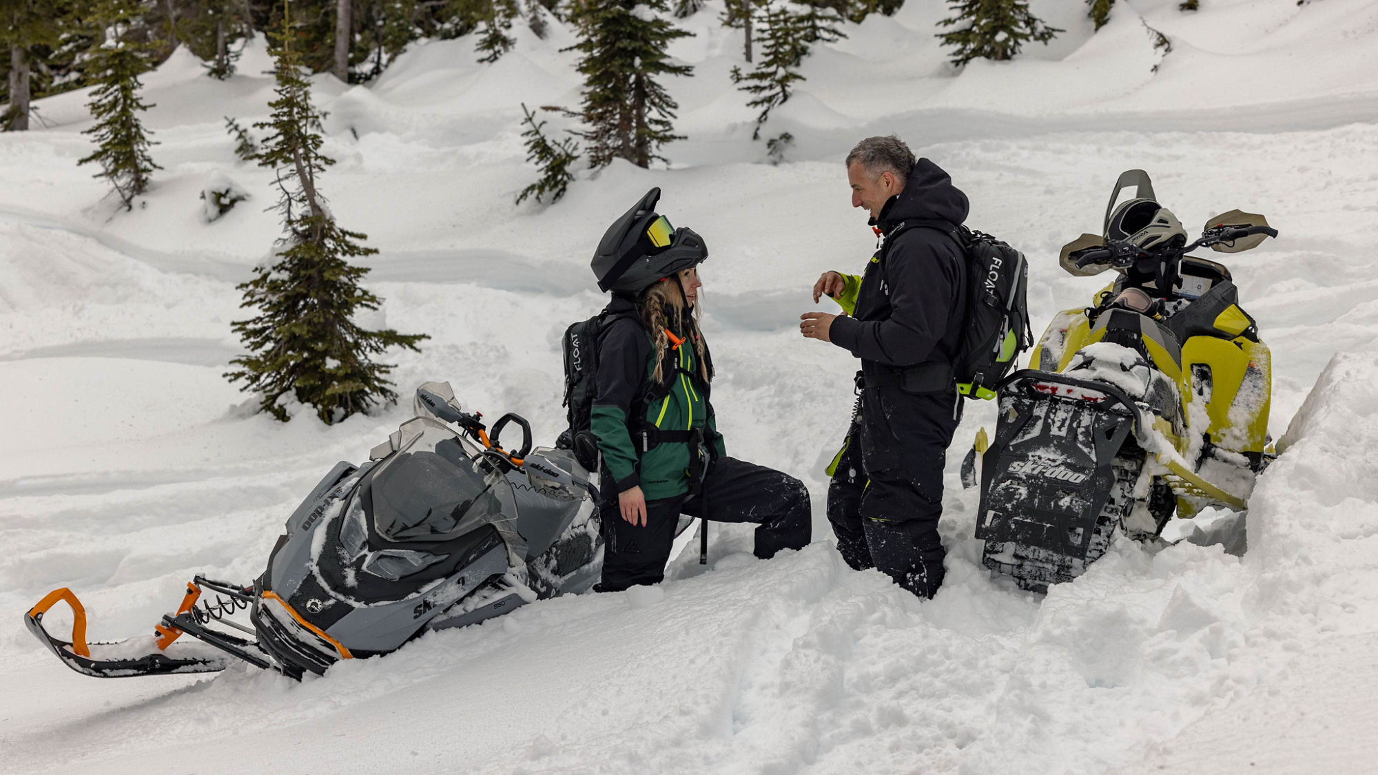 Deux motoneigistes discutant à côté de leur motoneiges Ski-Doo