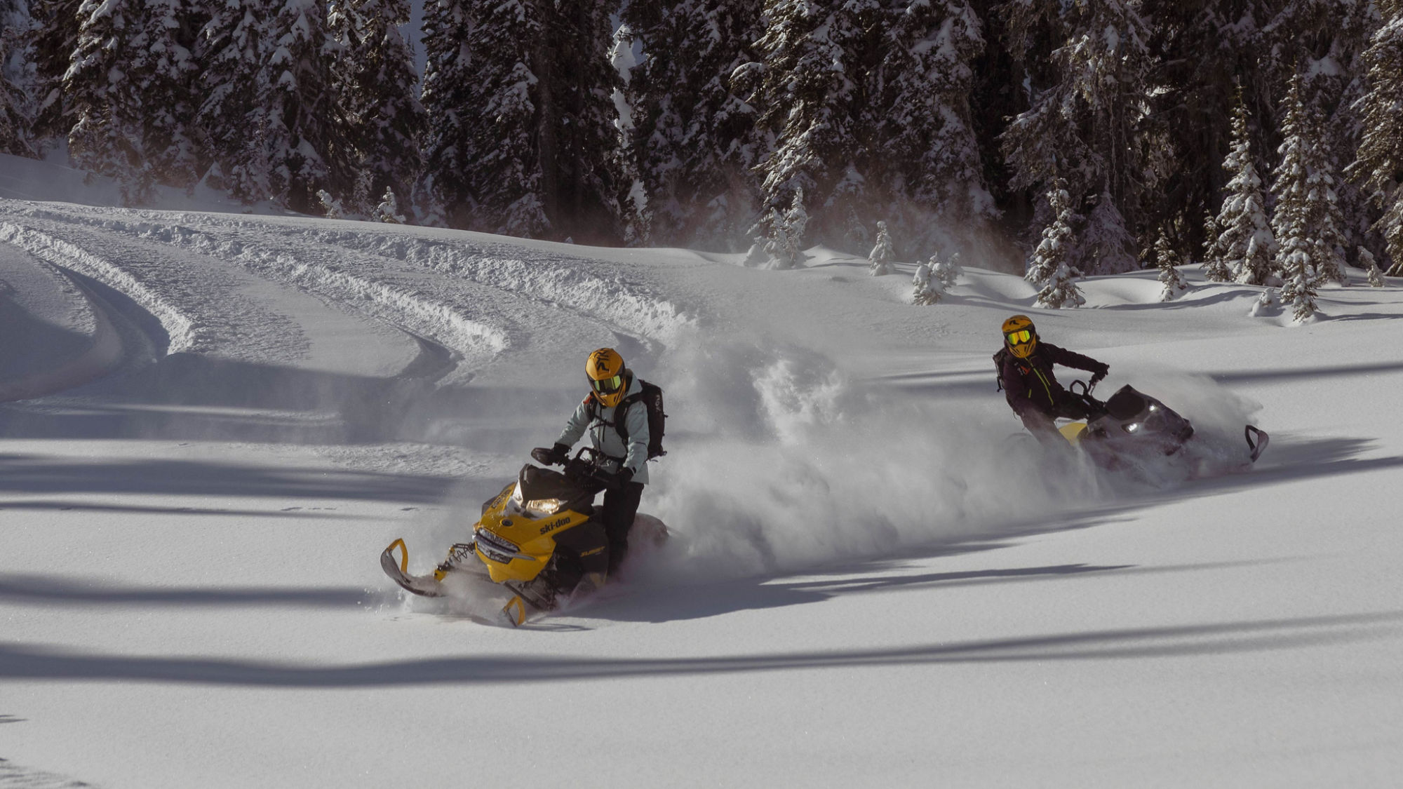 Kaksi Ski-Doo syvälumimoottorikelkkaa siksakkimassa lumessa
