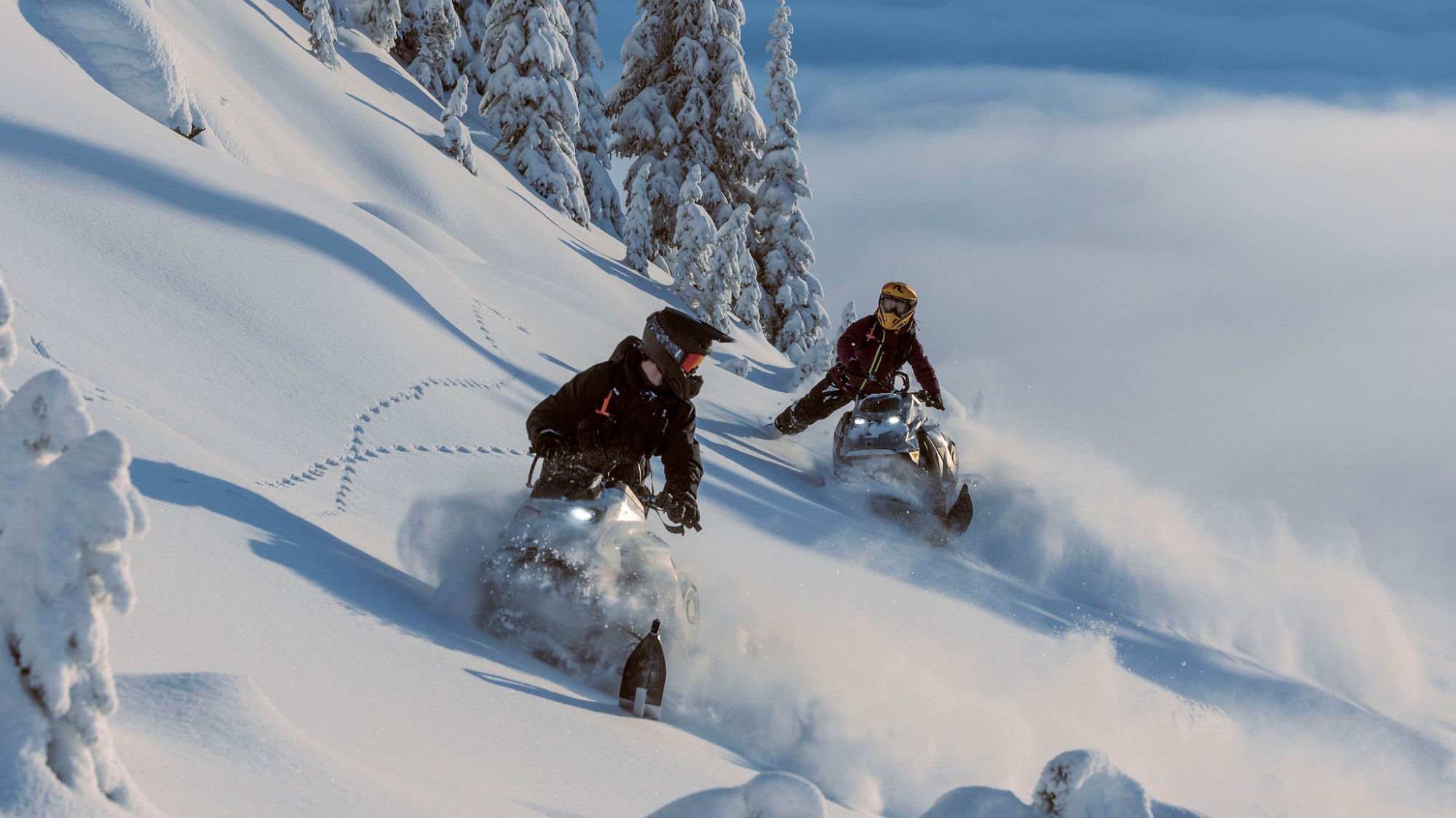 Två 2025 Ski-Doo snöskotrar tävlar på ett snöigt berg