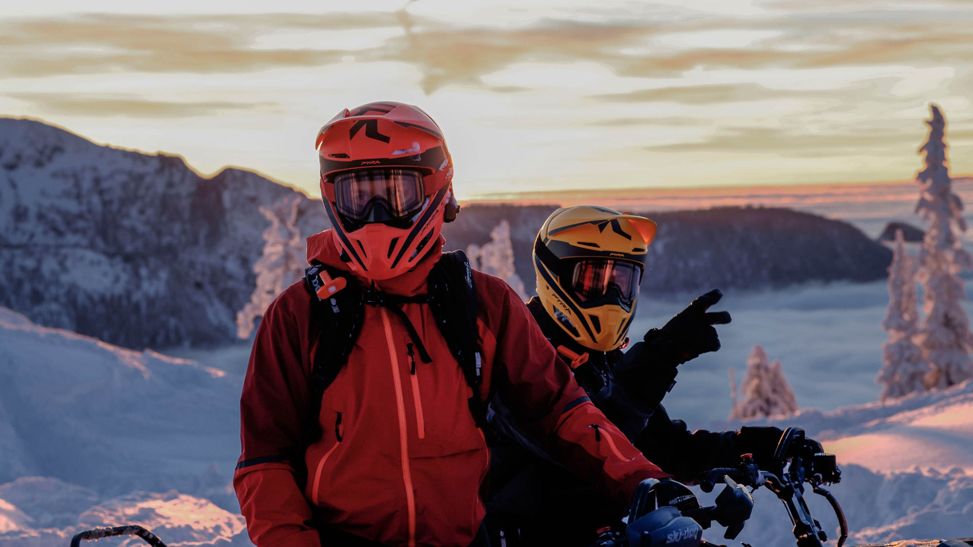 Two snowmobile riders taking a break equipped with their Pyra safety helmet