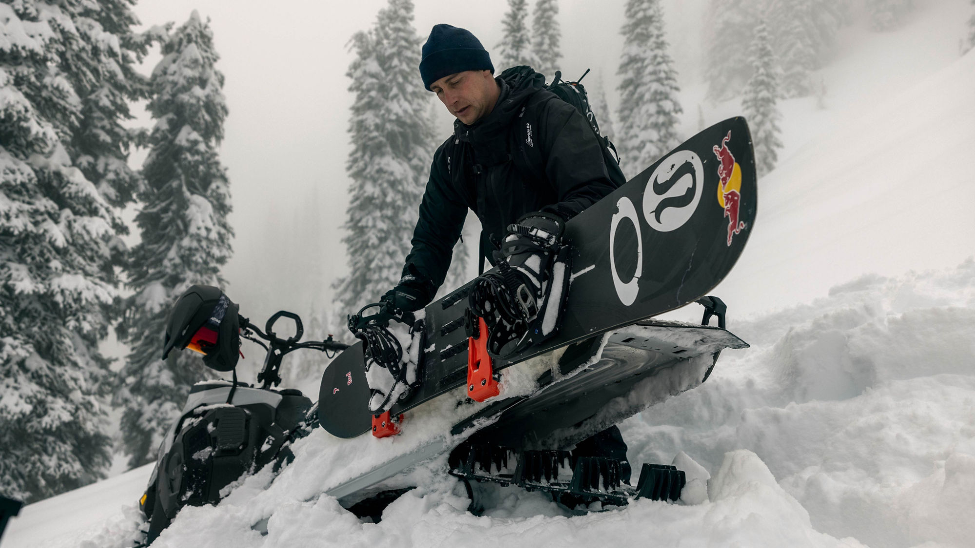 Man attaching his snowboard to his 2025 Ski-Doo Summit Edge snowmobile.