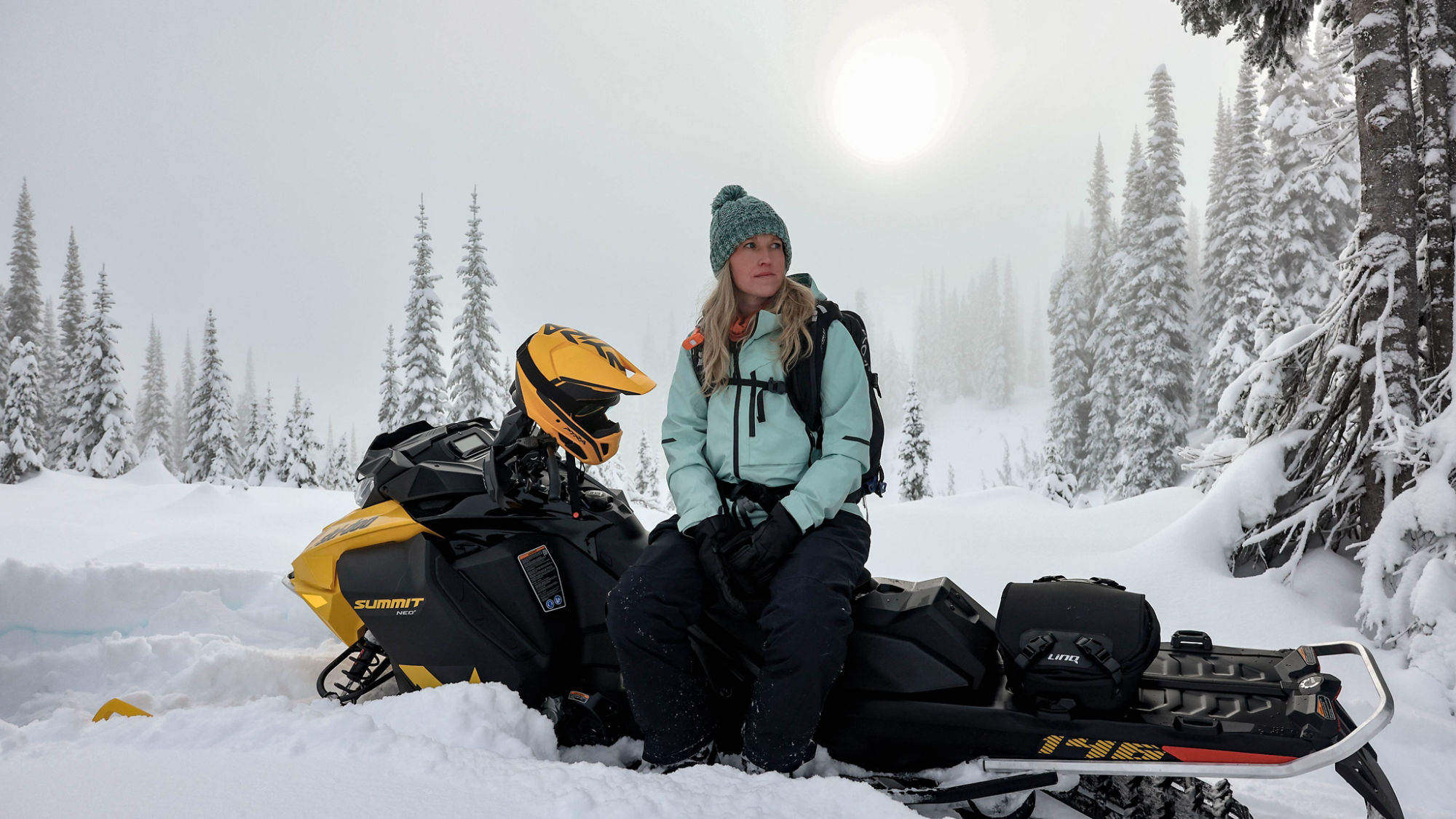 Femme qui prend une pause sur sa motoneige neige profonde Ski-Doo NEO+ 2025