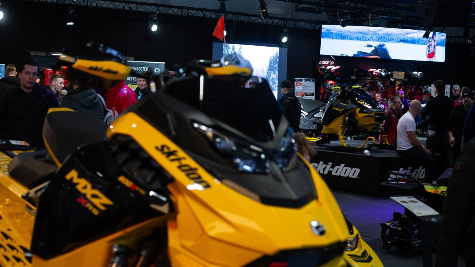 Folk samlet rundt Ski-Doo-snøscootere i en messehall