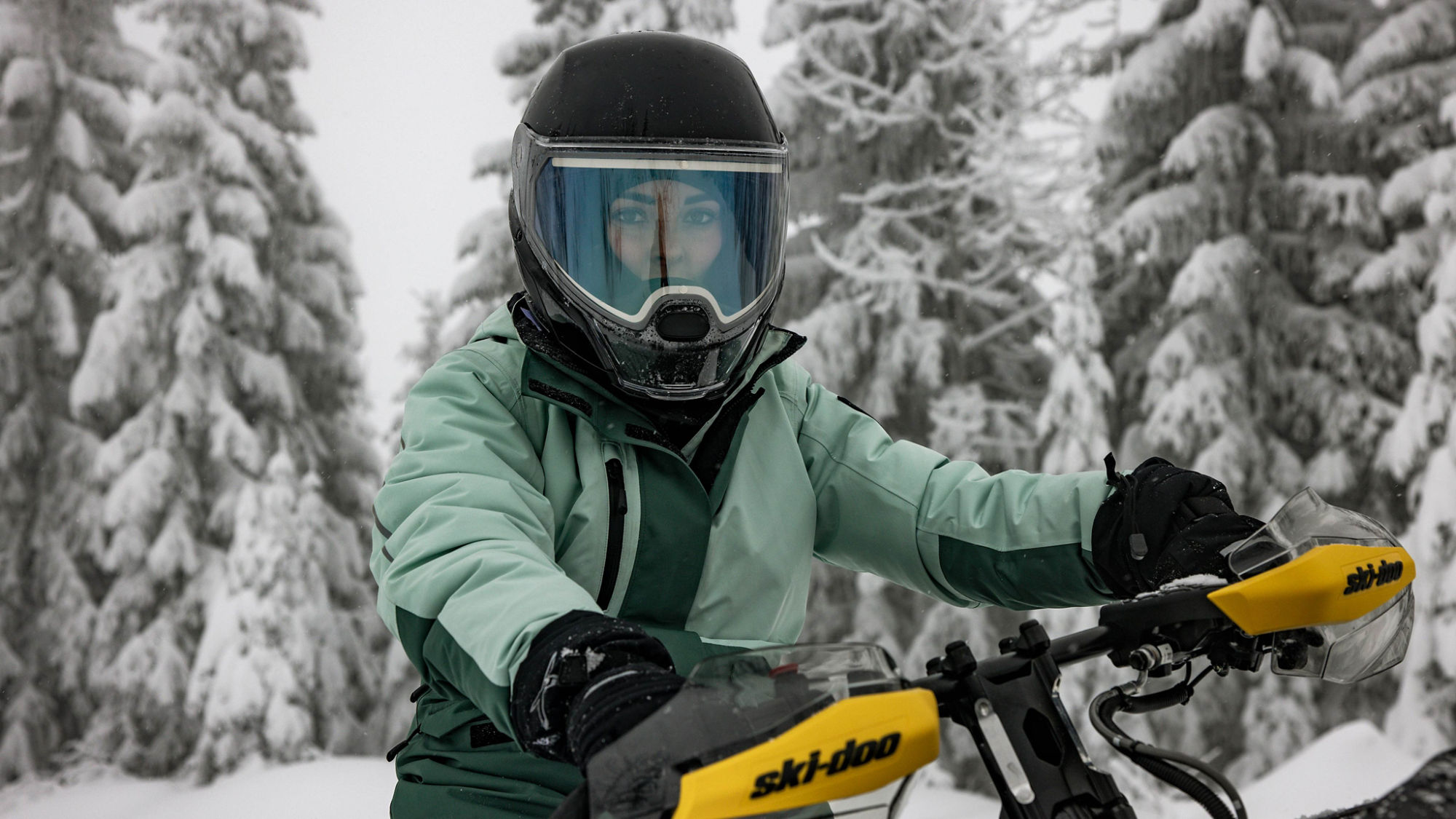Woman wearing a safety helmet sitting on a 2025 Ski-Doo MXZ NEO