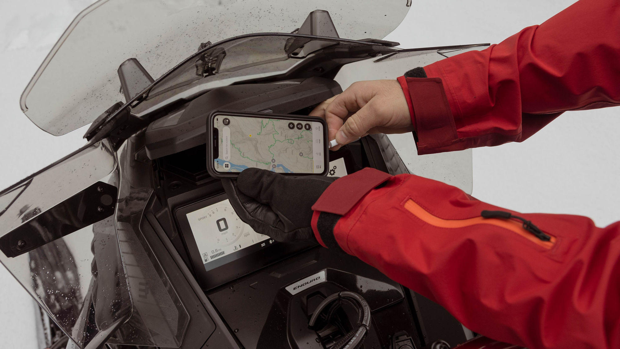 Motoneigiste qui connecte son téléphone mobile à l'écran 10.25 pouces du Ski-Doo Renegade 2025