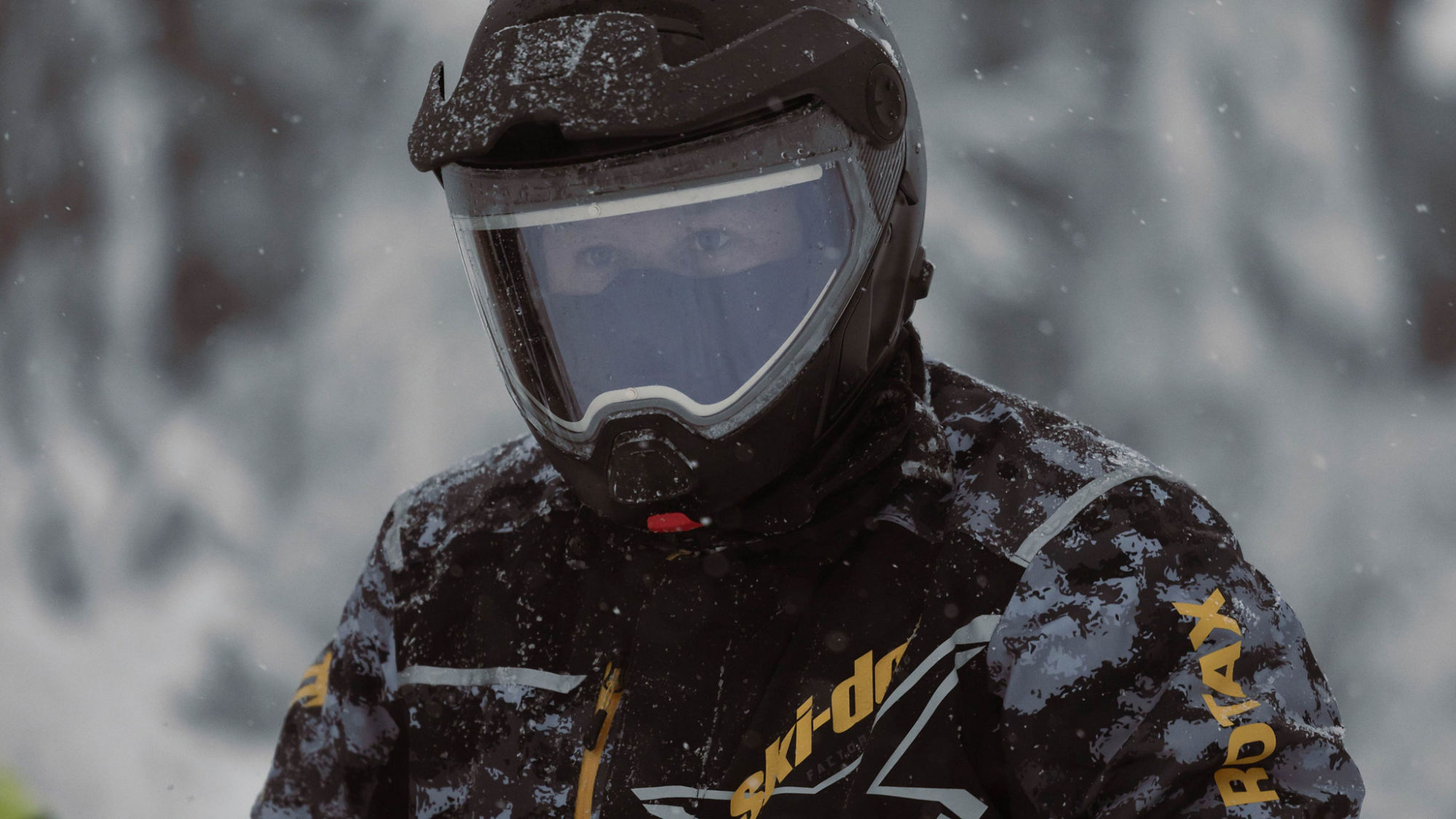 Snowmobile rider wearing a Ski-Doo brand jacket and an Advex safety helmet