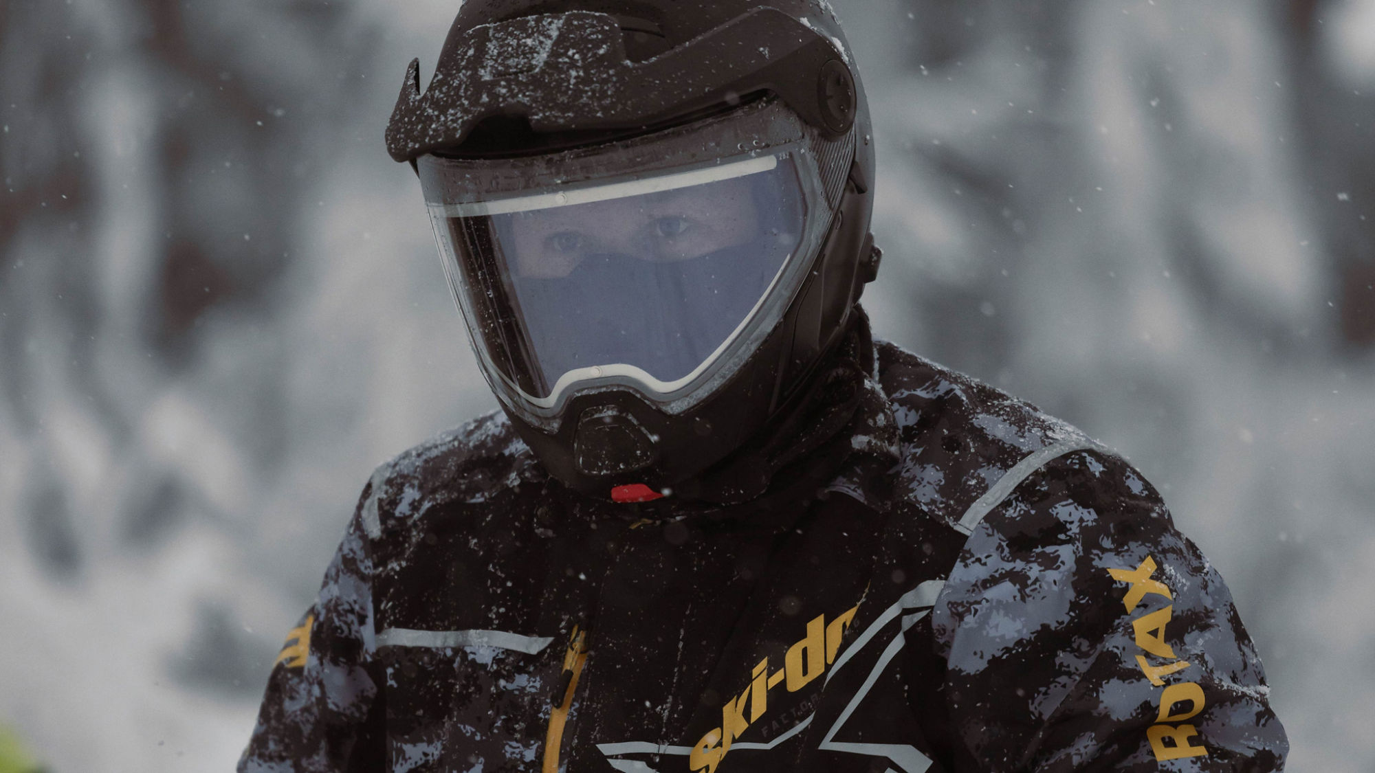 Conducteur de motoneige portant un manteau Ski-Doo et un casque de sécurité Advex