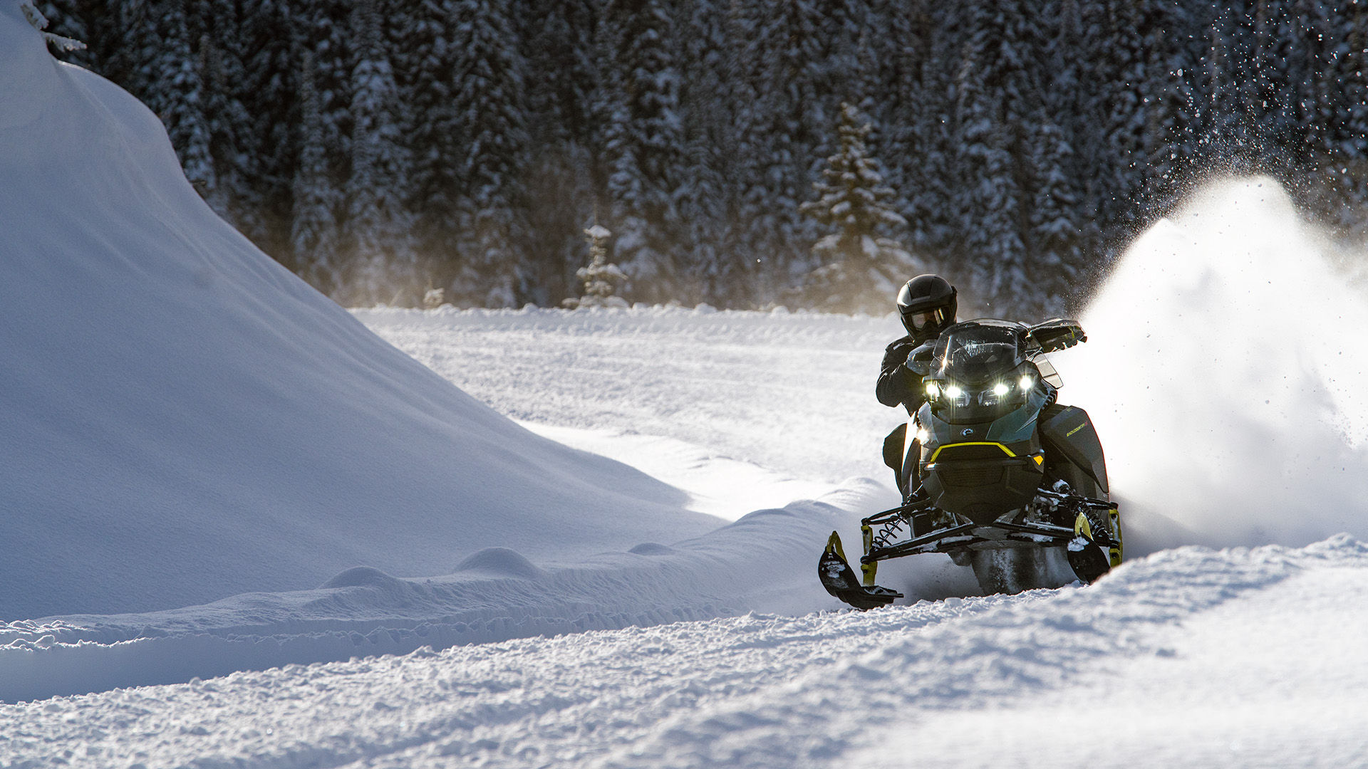 Snowmobiler riding a 2026 Ski-Doo crossover snowmobile in a snowy forest.