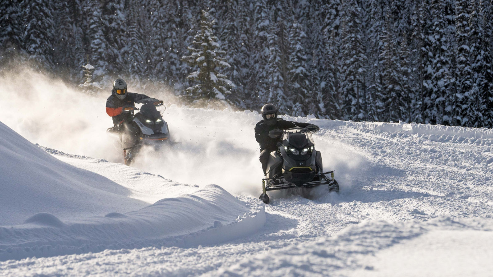 Two Ski-Doo snowmobiles cornering on snowy trail