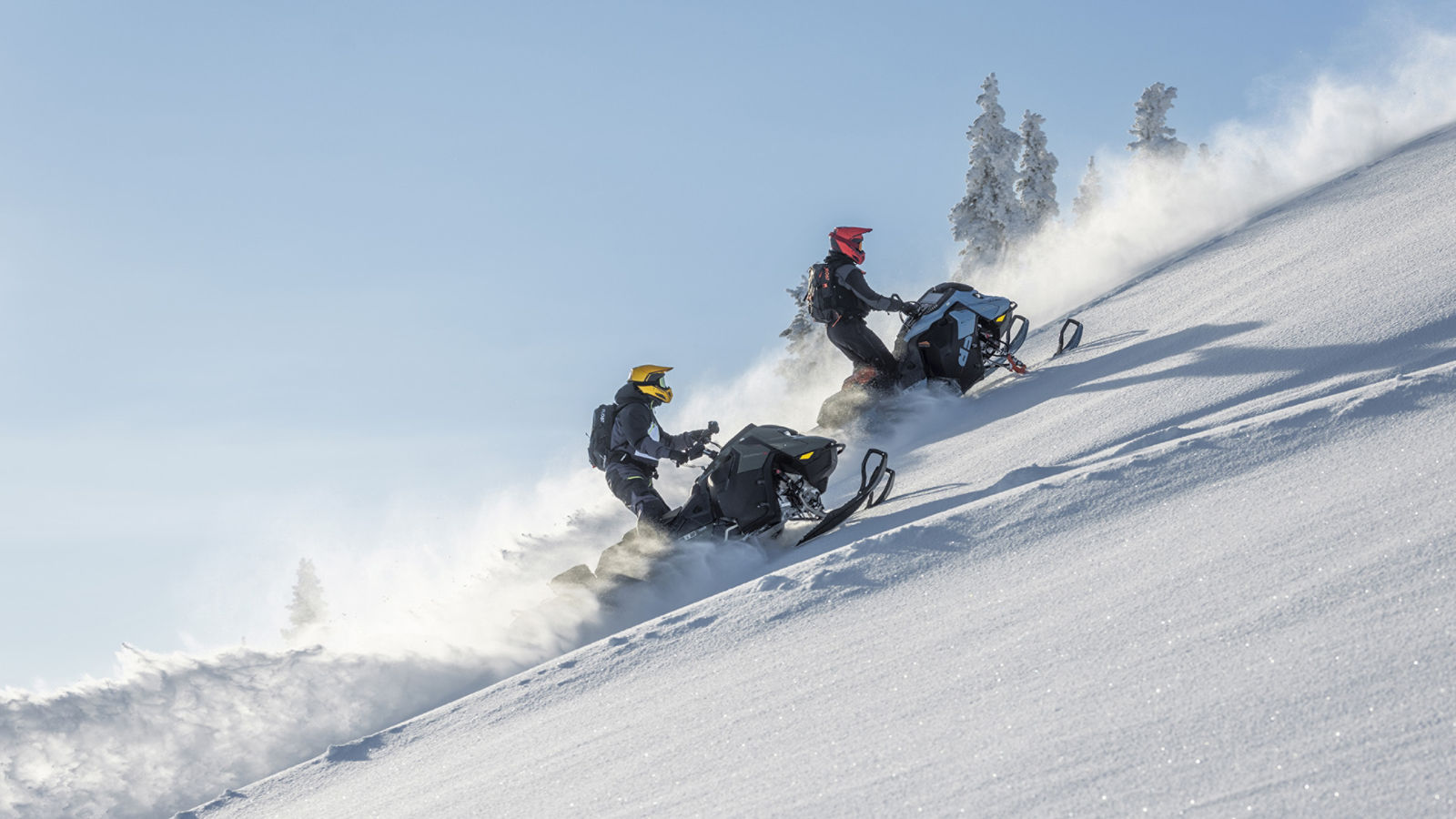 Two snowmobilers riding up a snowy mountain on Ski-Doo snowmobiles