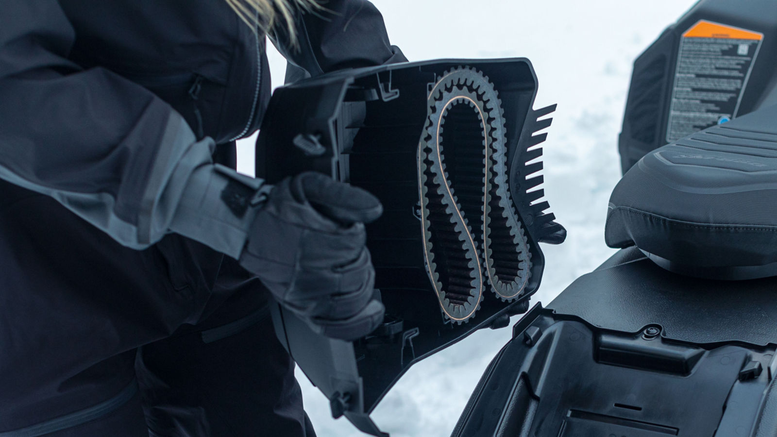 Ski-Doo rider holding a snowmobile drive belt