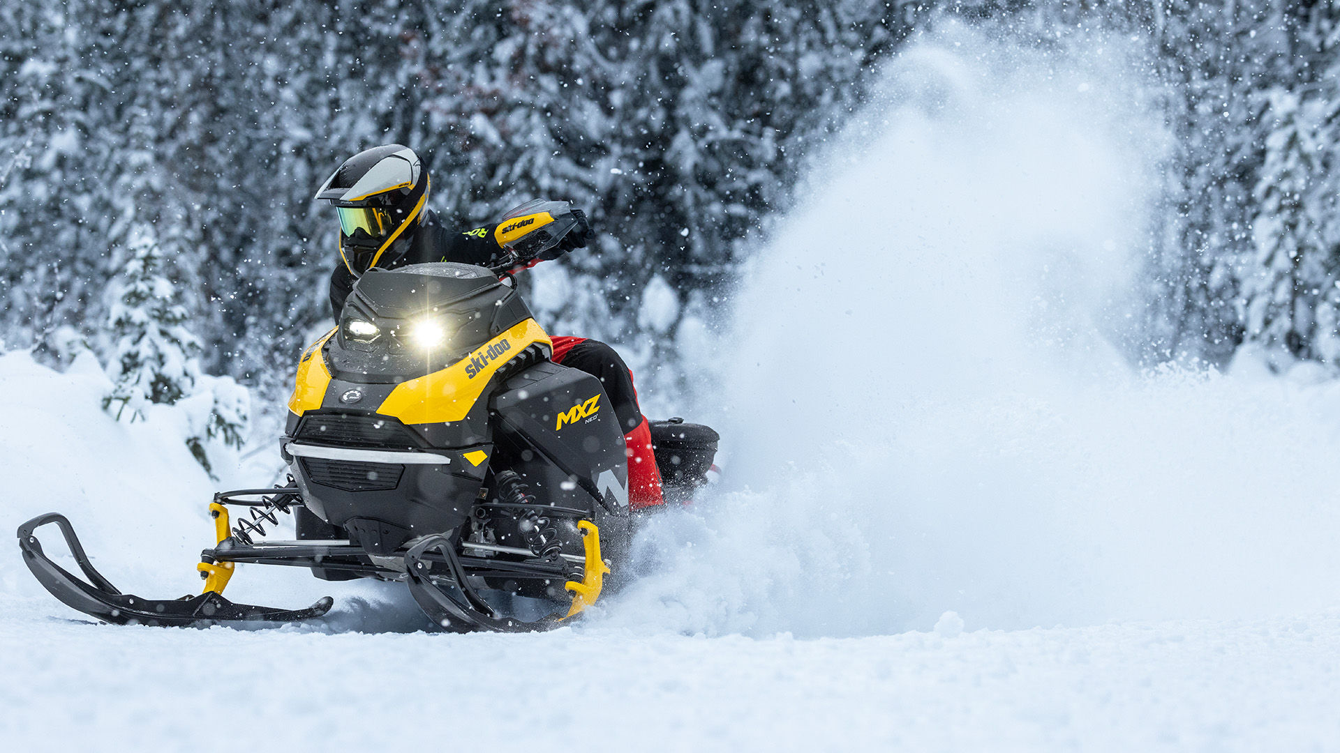 Snowmobiler riding a 2026 Ski-Doo MXZ NEO+ snowmobile in a snowy forest.