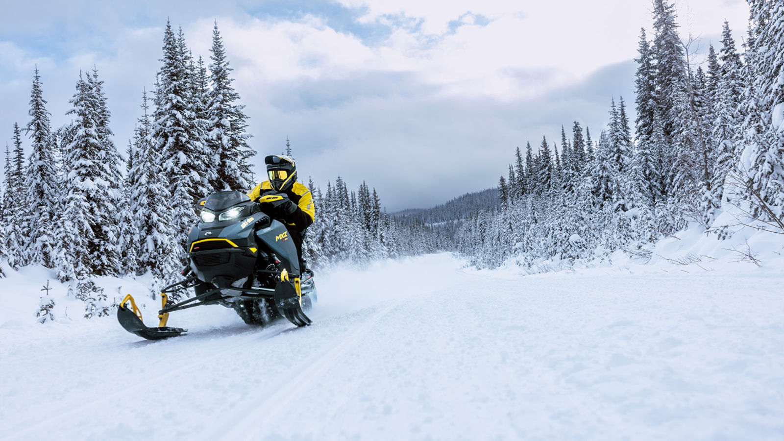 Snöskoteråkare som kör en 2026 Ski-Doo MXZ X-RS i en snöig skog.