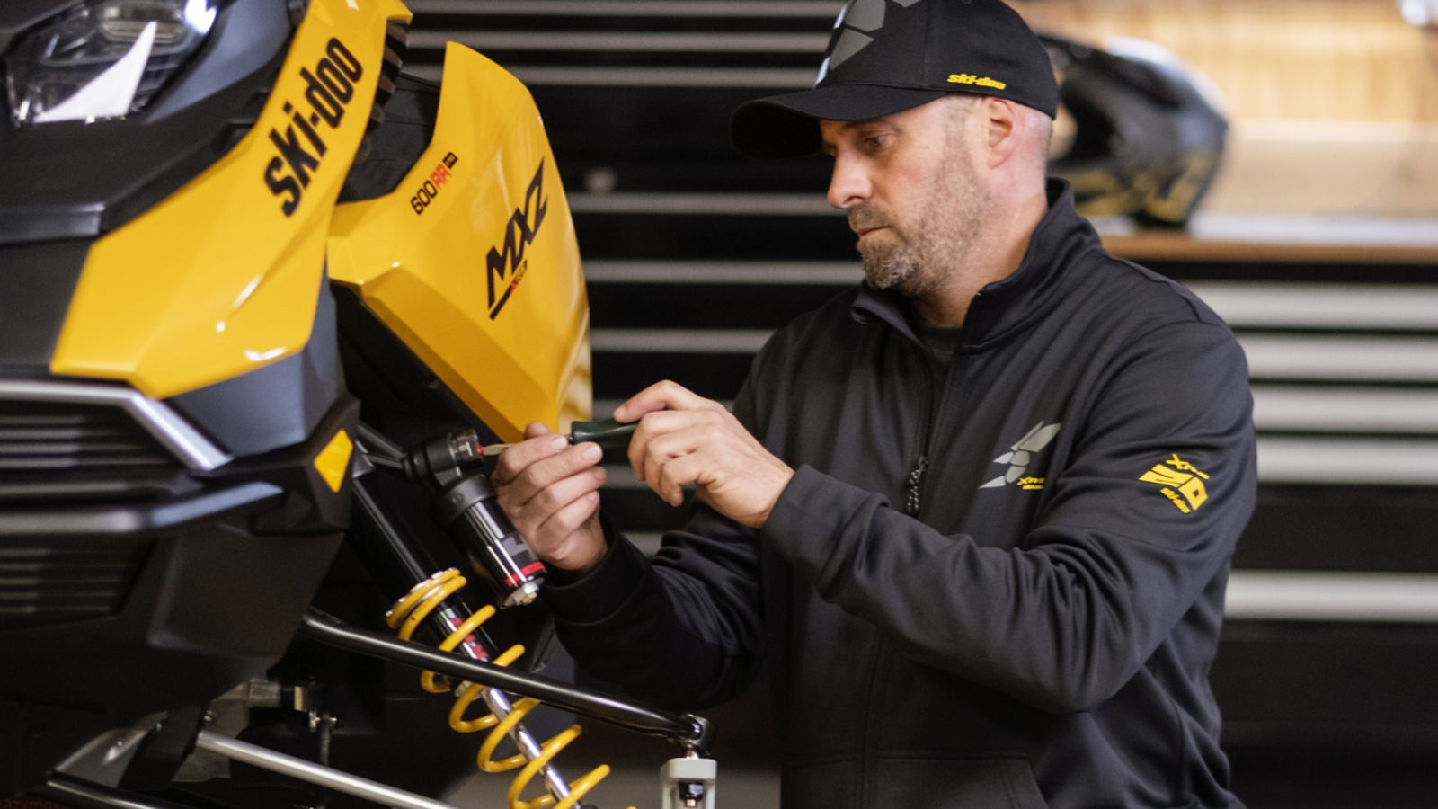 Man doing suspension maintenance on his Ski-Doo snowmobile